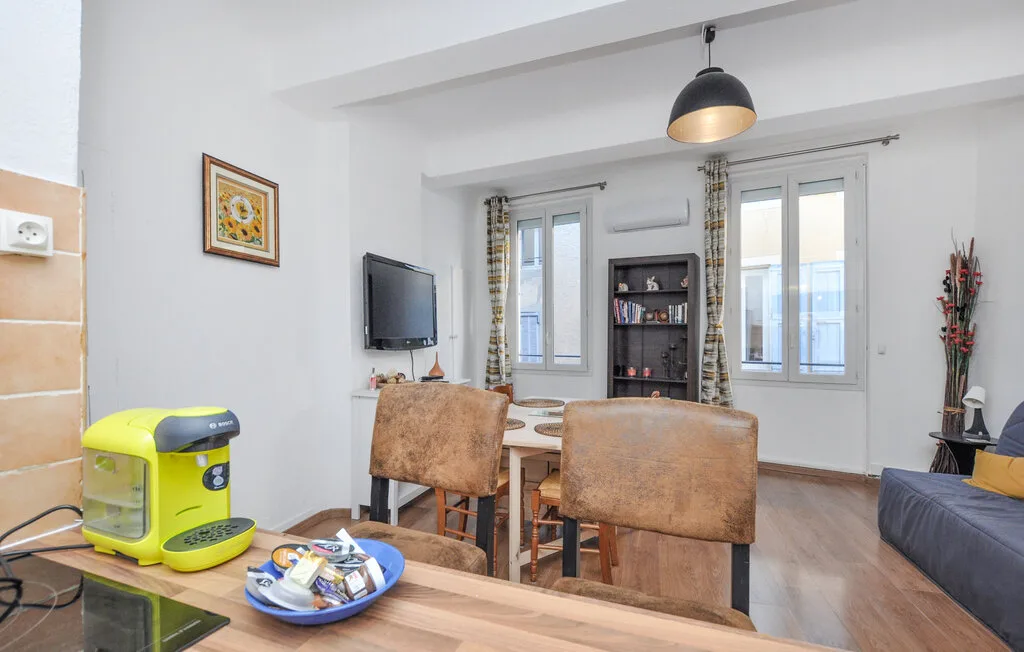 Una luminosa sala de estar y comedor tiene una mesa, asientos y ventanas altas.