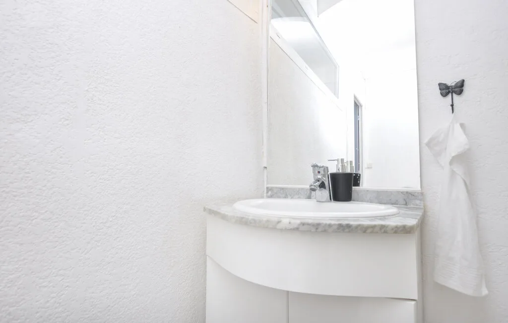 Un lavabo de baño con un lavamanos y una toalla colgada en la pared.