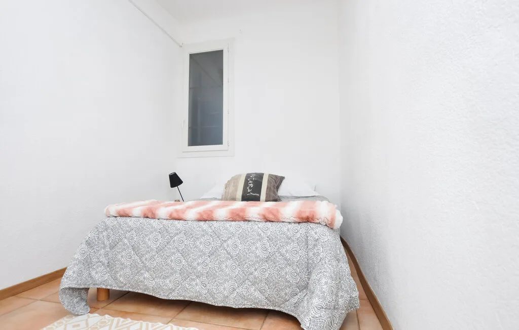 Un dormitorio sencillo con una cama bajo una ventana estrecha.
