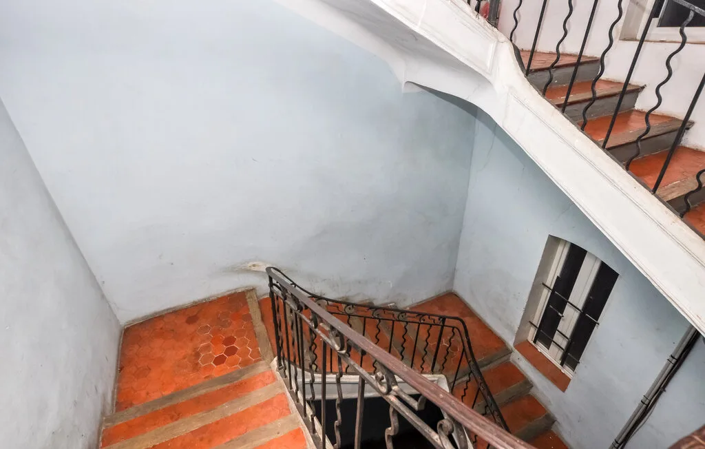 Una escalera interior con peldaños de color terracota y barandillas metálicas oscuras.