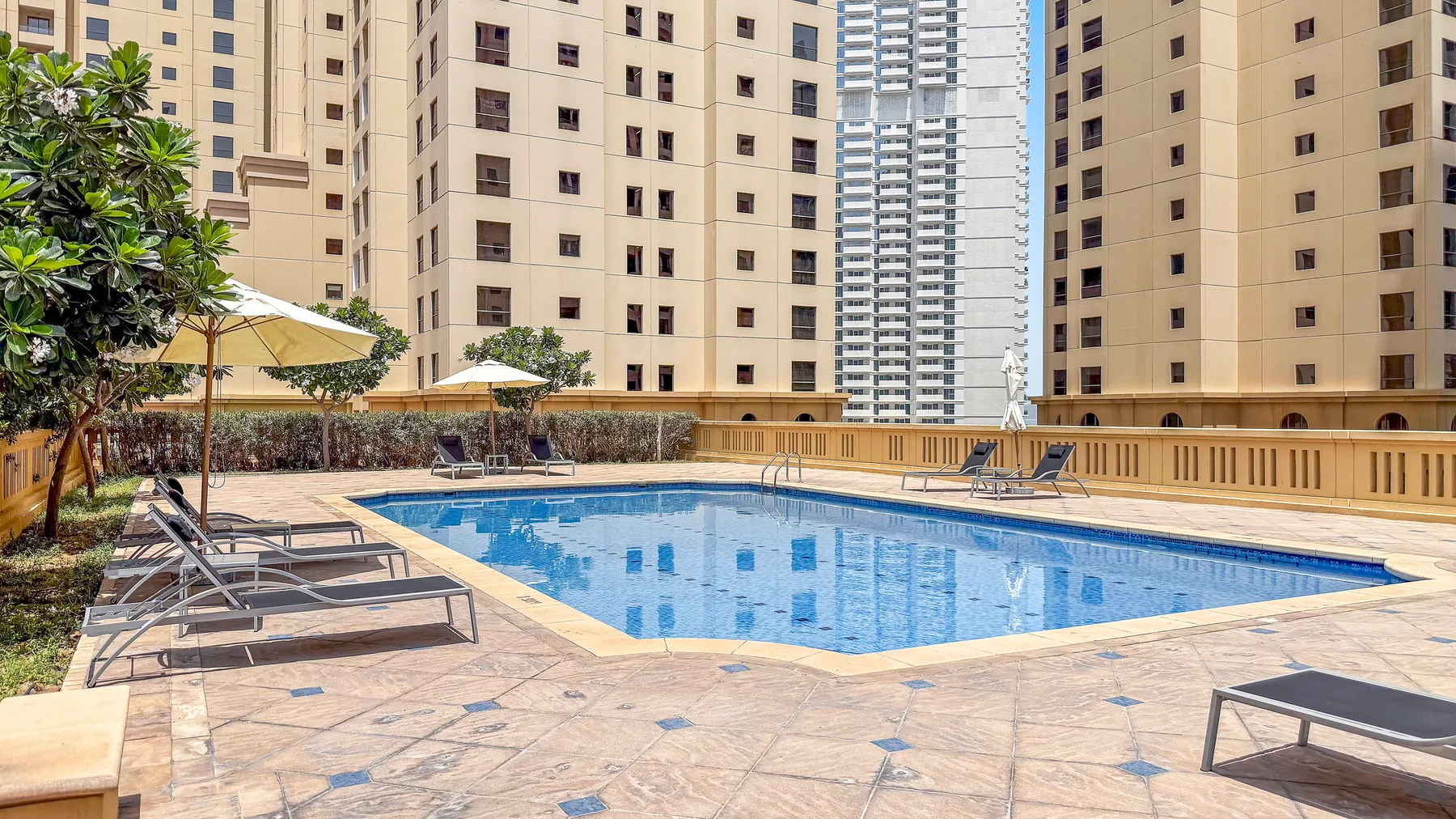 An outdoor swimming pool sits beside tall residential buildings.