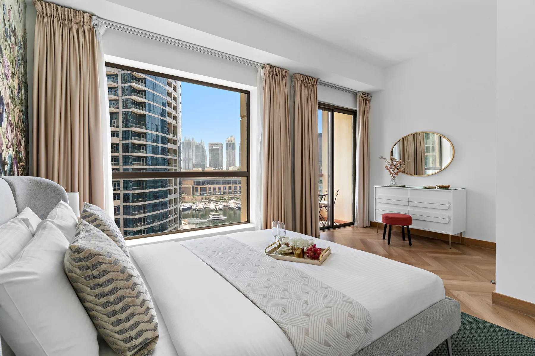 A bright bedroom with a bed, large windows, and a city view.