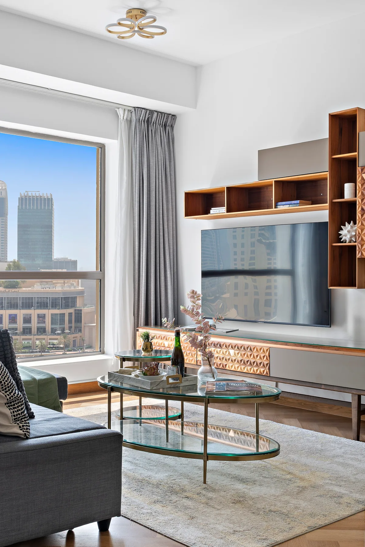 A bright living room with a television, seating, and a large window.