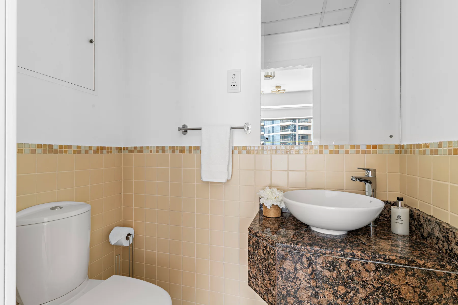 A bathroom with a white sink above a dark stone countertop.