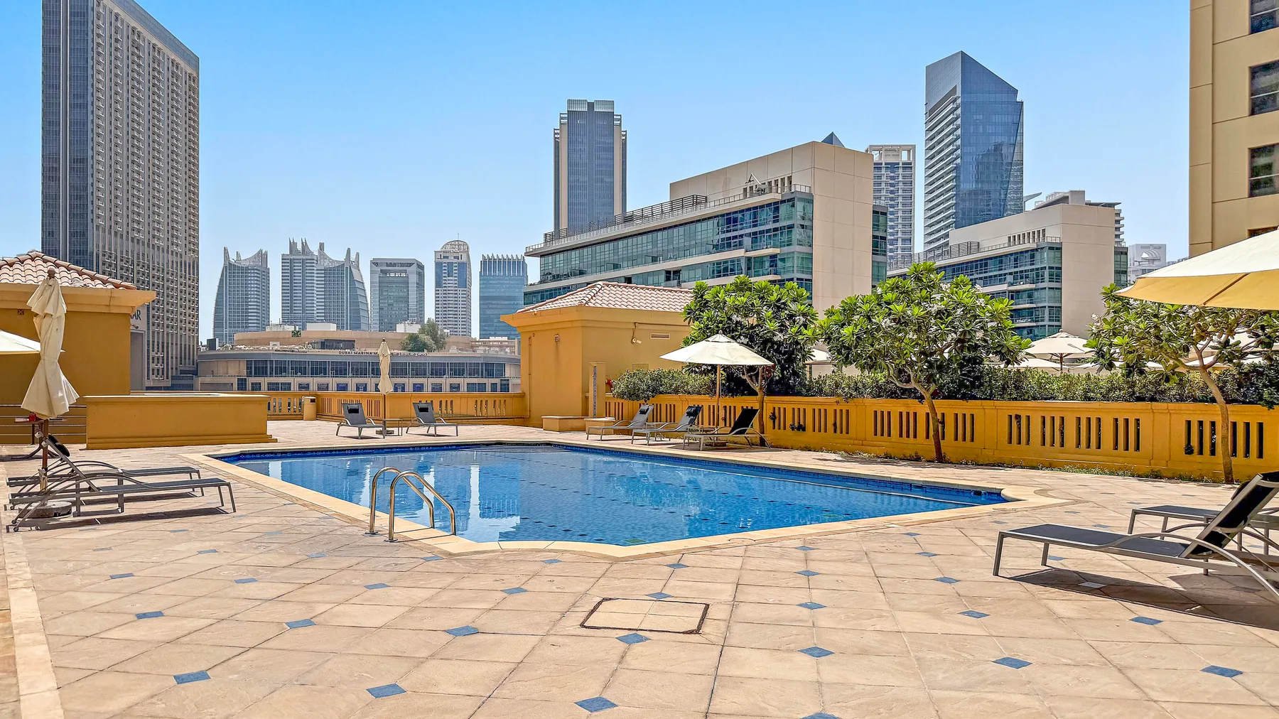 A rooftop swimming pool is surrounded by tiled deck space and lounge seating.