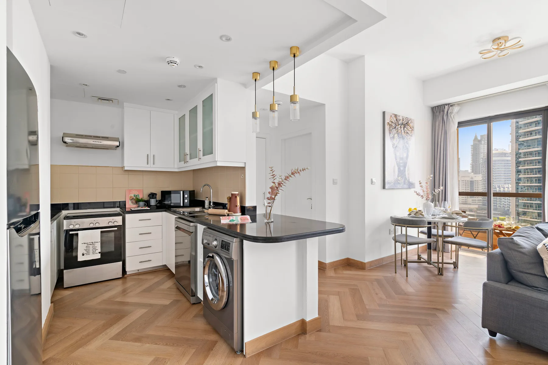 An open-plan kitchen and living area with a dining table beside the windows.