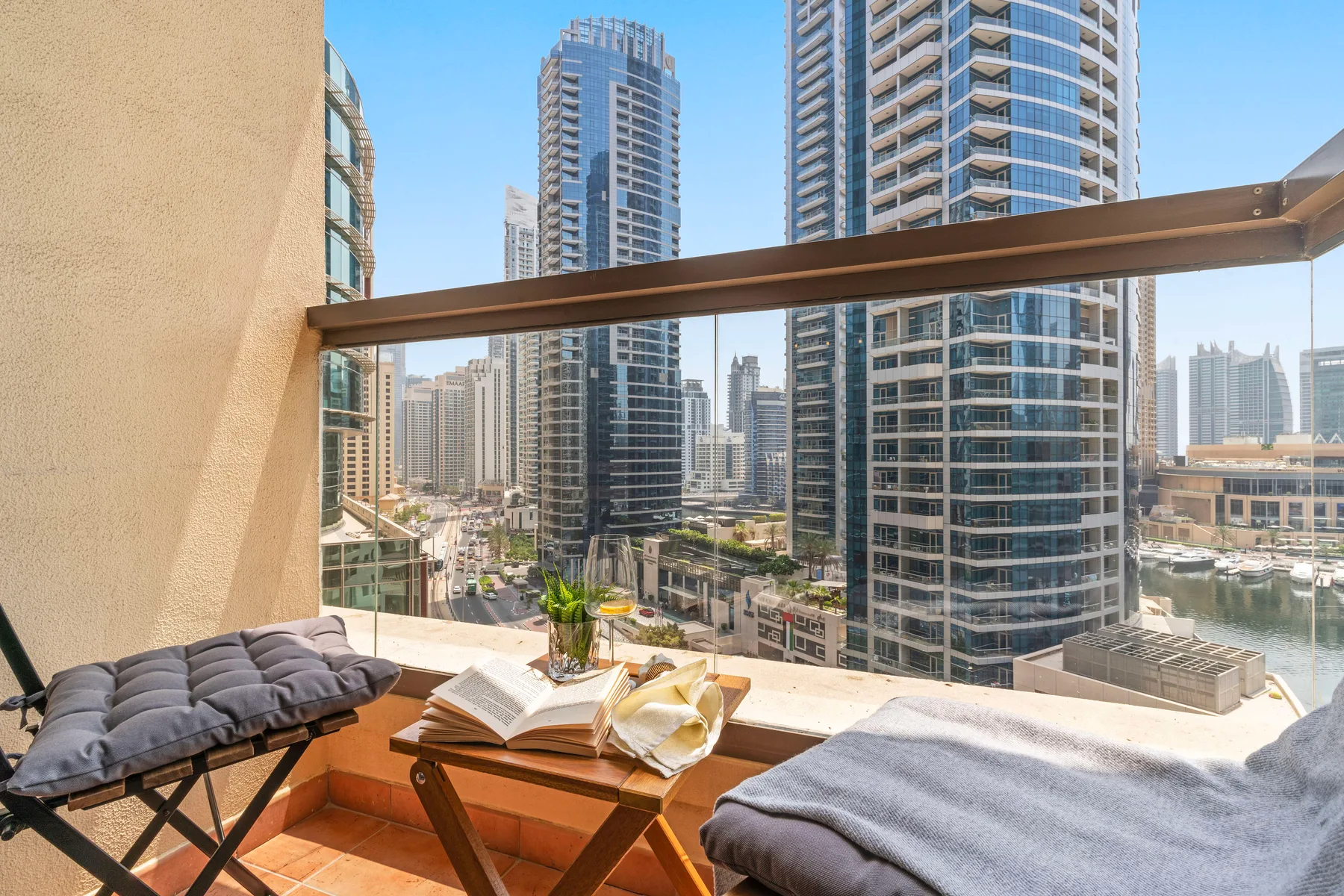 A balcony seating area overlooks a city skyline, with cushions and a small table.