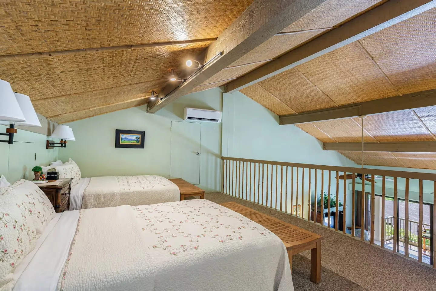Un dormitorio con dos camas, un techo inclinado y una barandilla de madera.