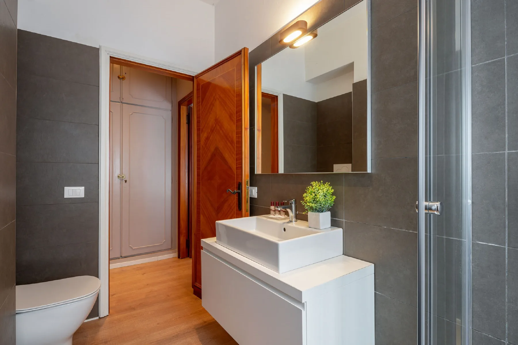 Un baño con lavabo, espejo de pared y ducha de vidrio.