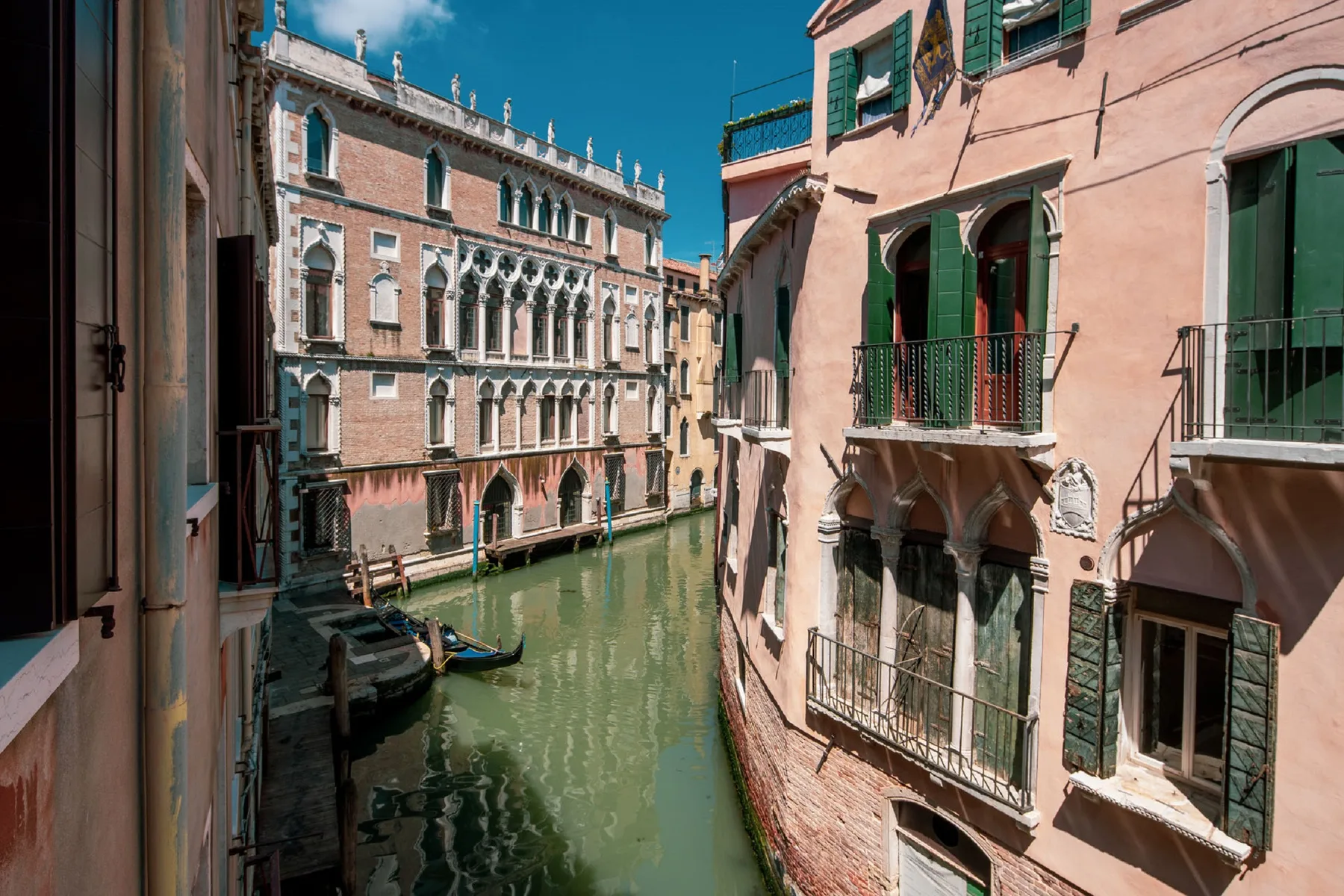 Un canal estrecho pasa entre edificios históricos bajo el sol.