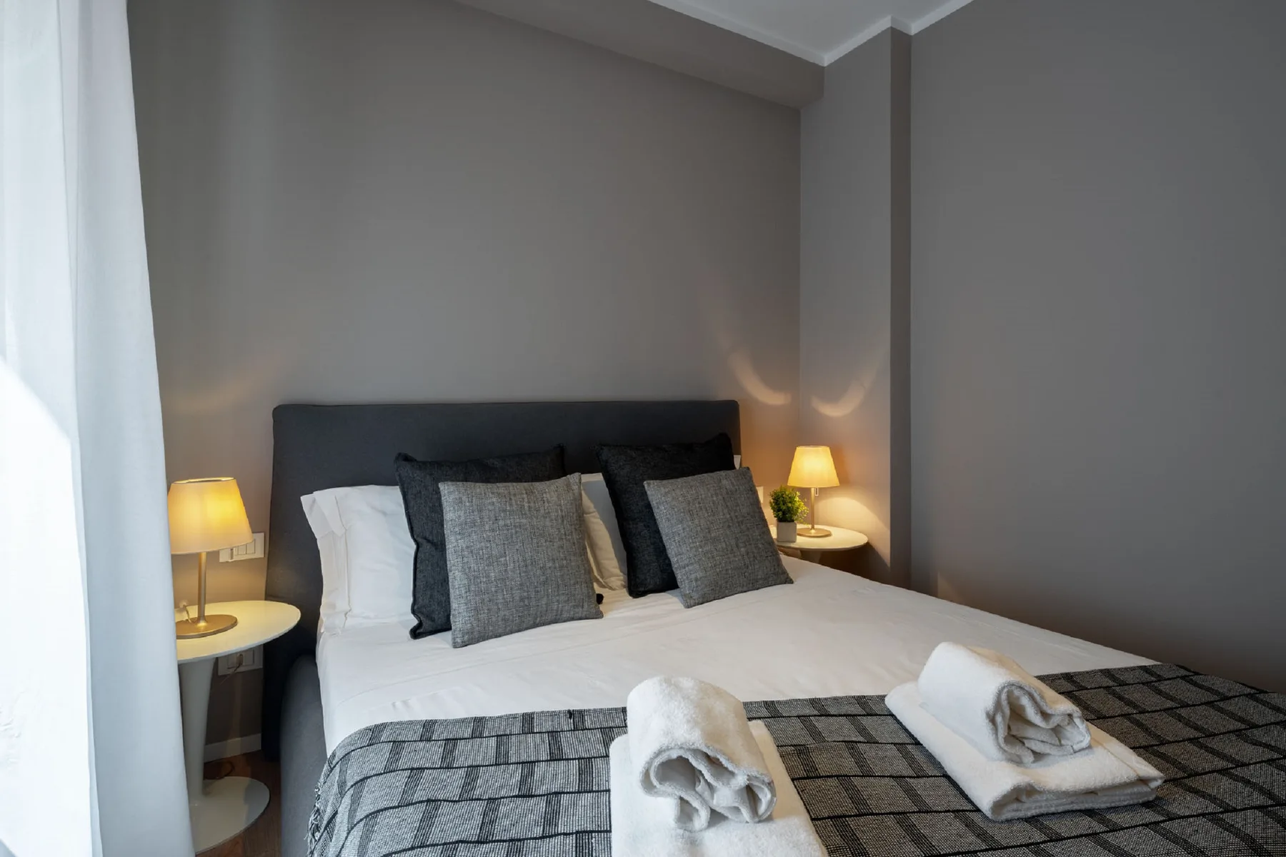Un dormitorio con una cama bien tendida y lámparas de mesilla.