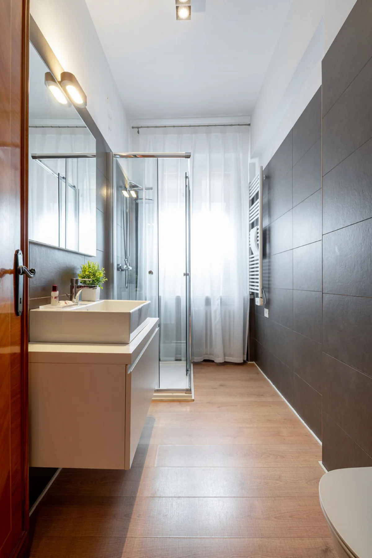 Un baño luminoso con ducha de vidrio y lavabo.