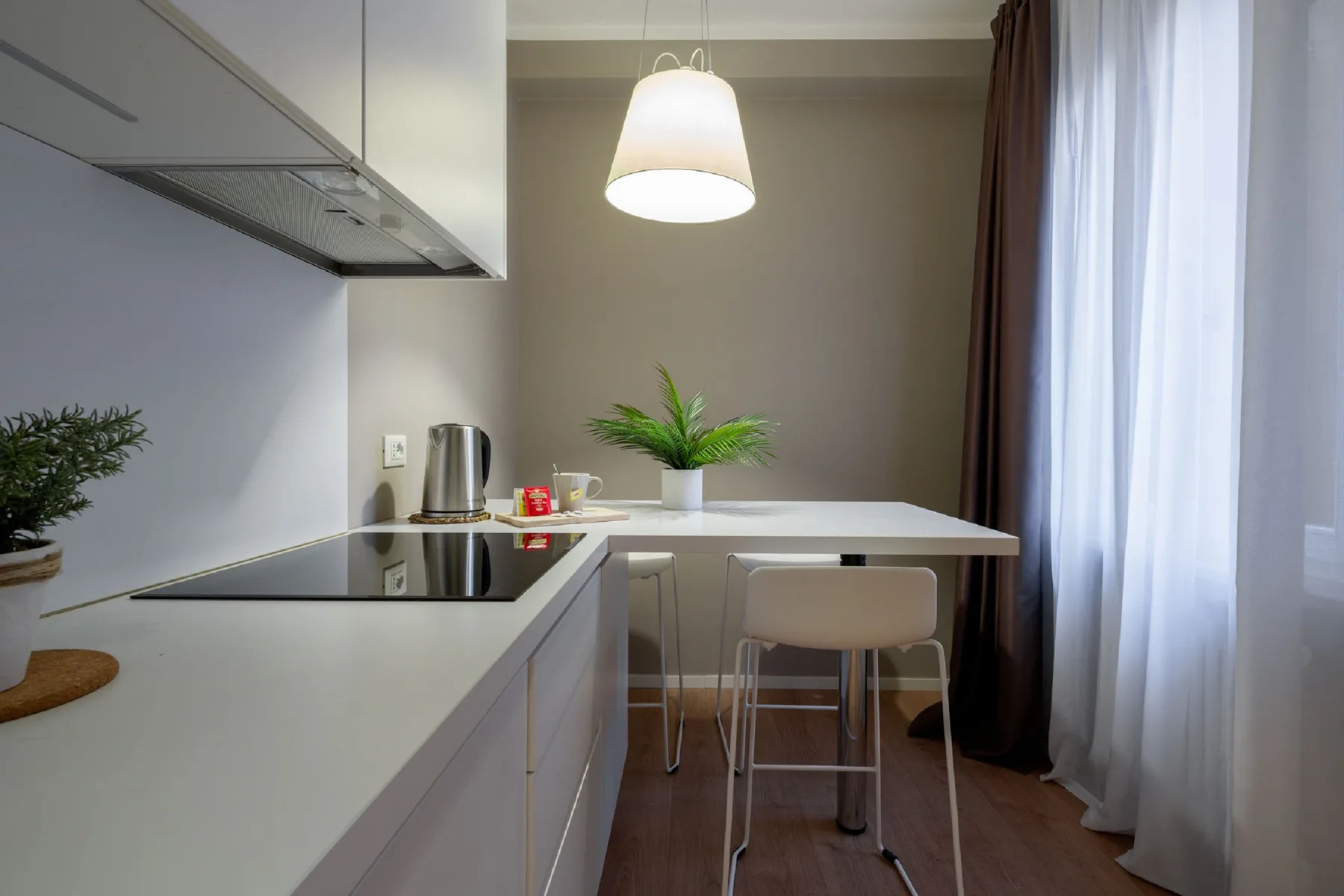 Una cocina compacta con encimera, placa de cocción y una pequeña zona para sentarse junto a la ventana.