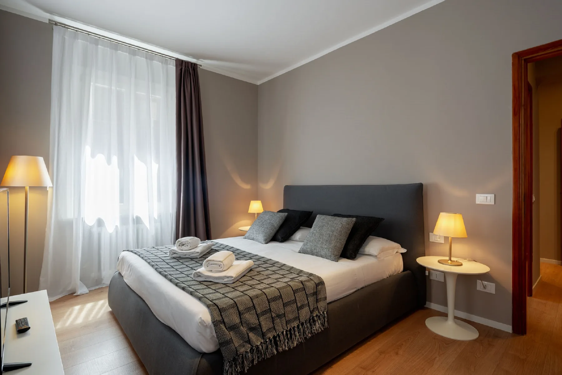 Un dormitorio con una cama, mesitas de noche y una ventana con cortinas.