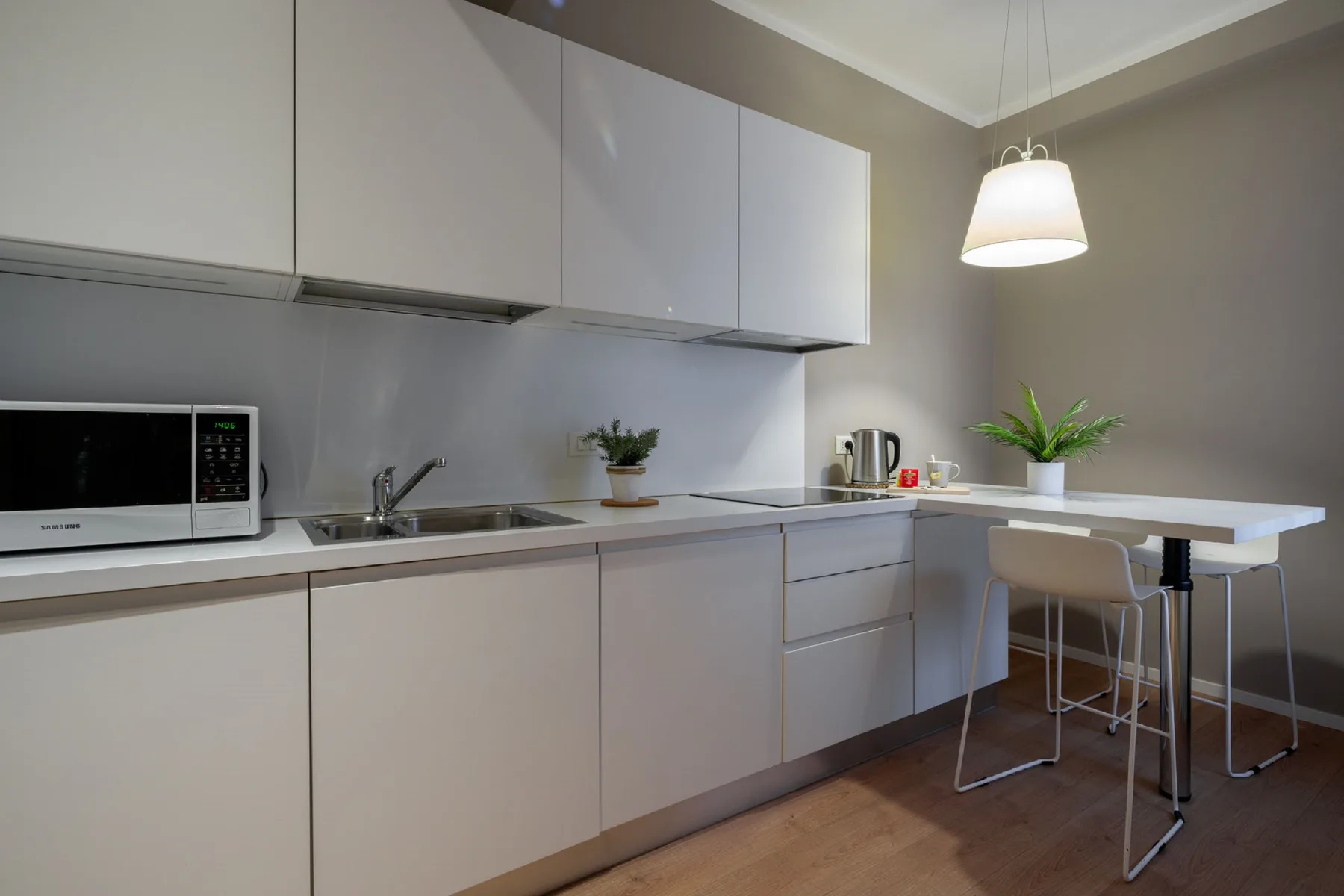 Una cocina moderna con gabinetes claros, una encimera y una pequeña mesa de comedor.