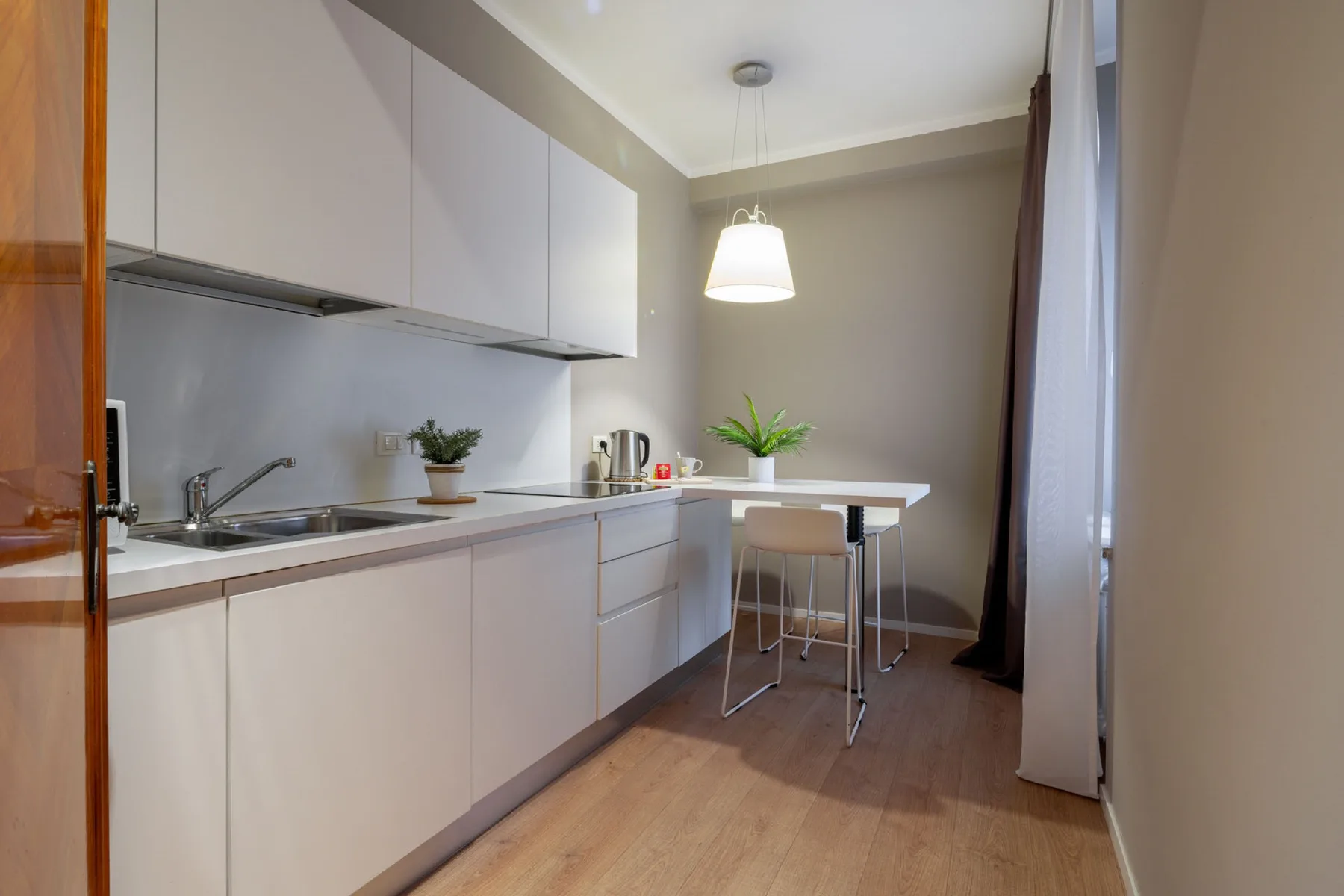 Una cocina compacta con gabinetes blancos y una mesa alta para comer.