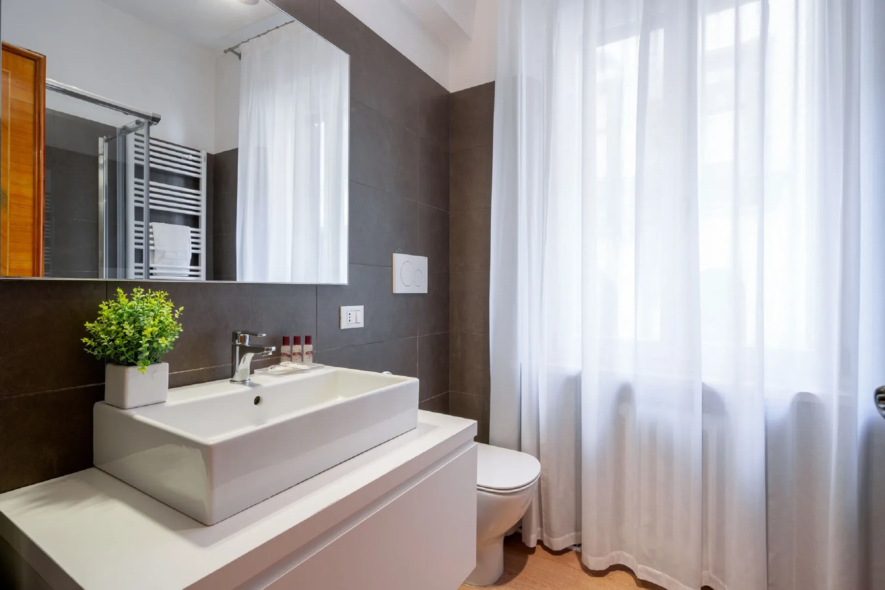 Un baño con lavabo, inodoro y cortinas translúcidas.