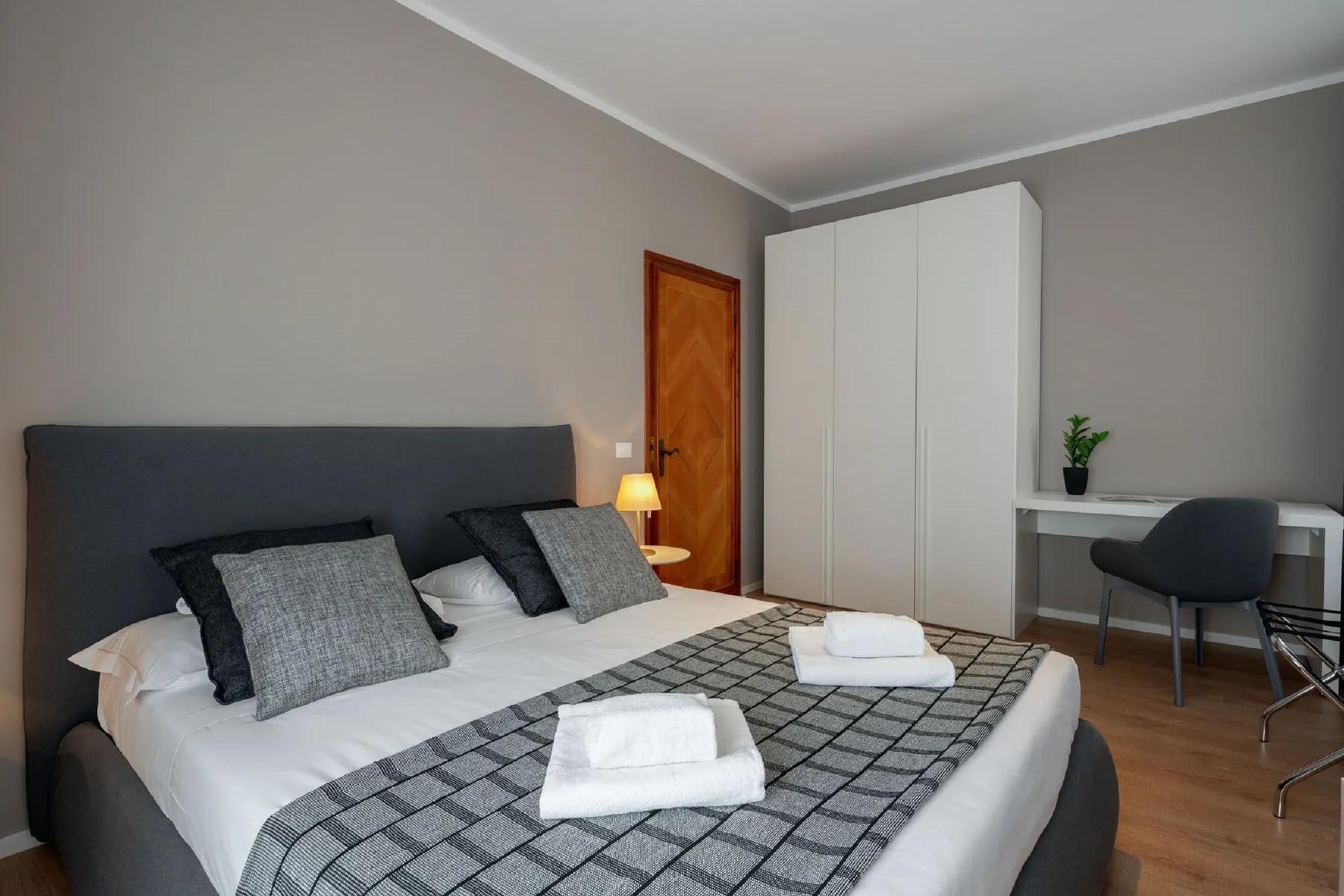 Un dormitorio con una cama doble, toallas dobladas y un armario.