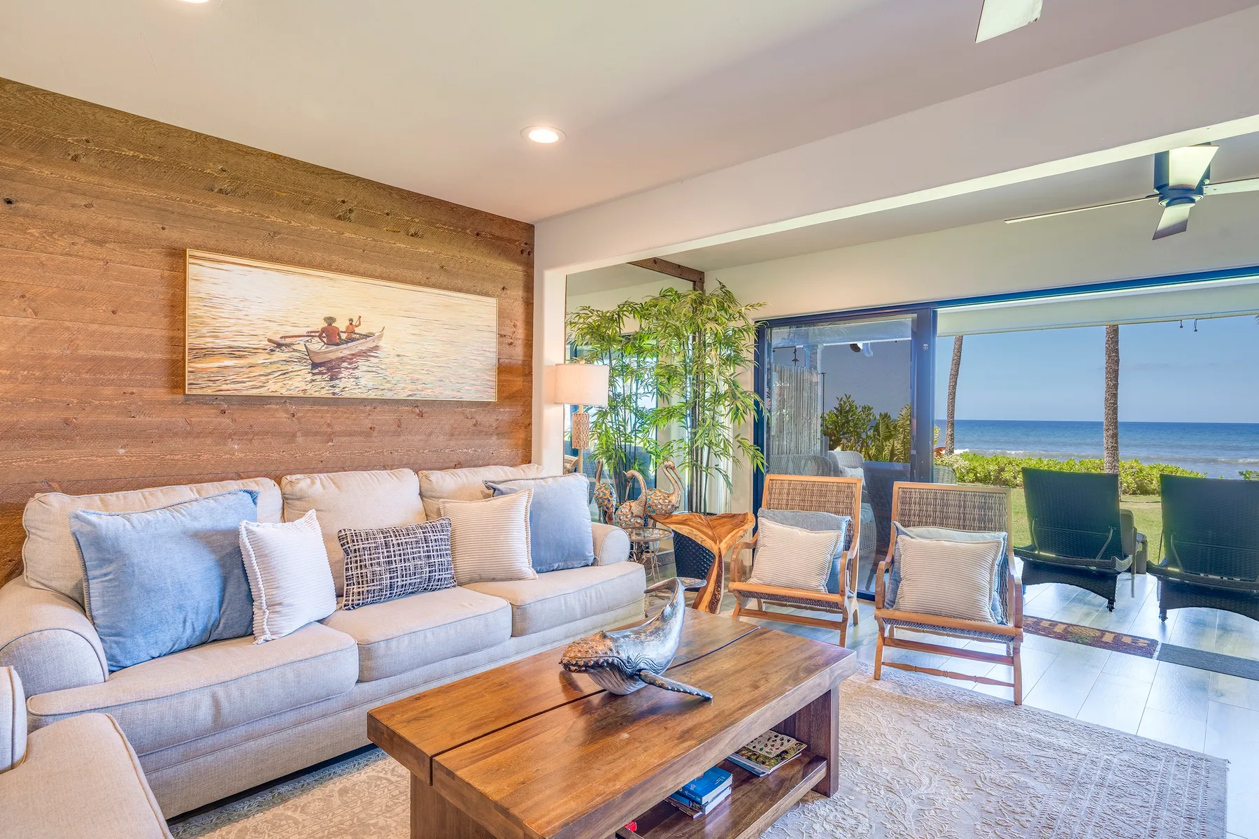 Una sala luminosa con asientos y una mesa de centro de madera junto al mar.