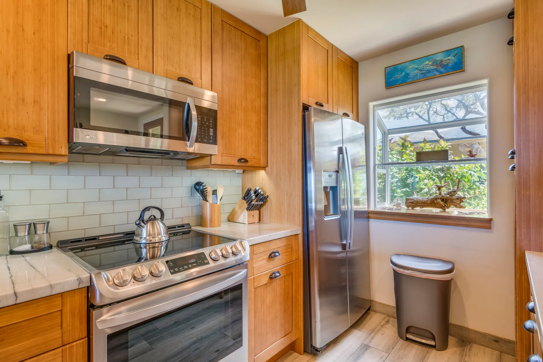 Una cocina con gabinetes de madera, electrodomésticos de acero inoxidable y una ventana amplia.