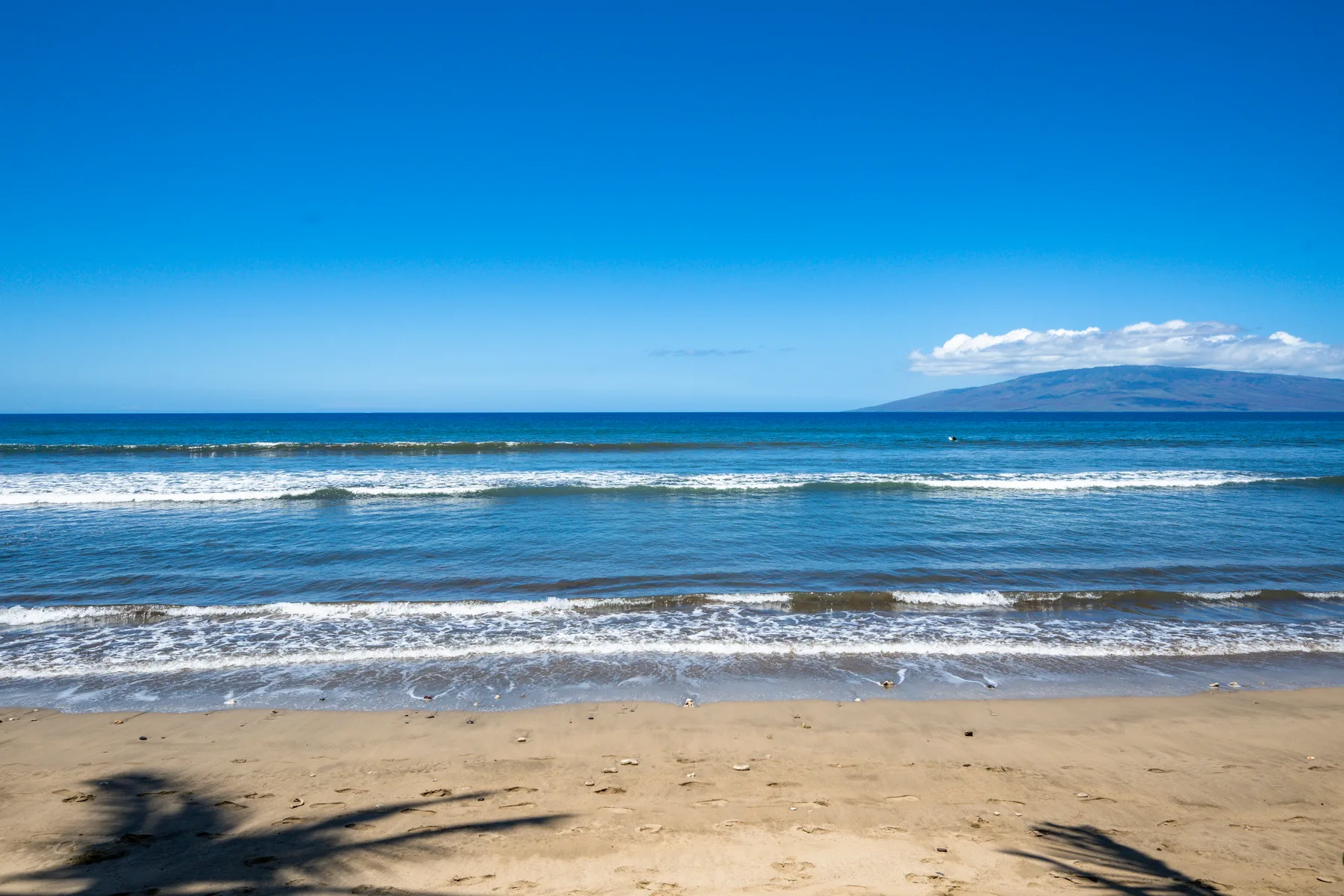 Una playa de arena se encuentra con aguas azules bajo un cielo despejado.