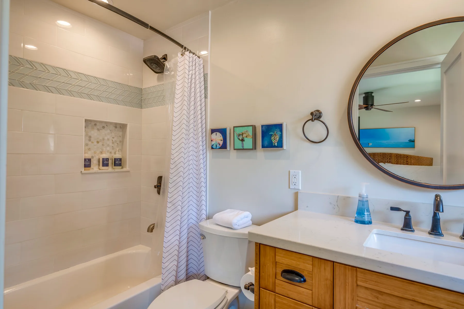 Un baño con ducha de azulejos, tocador y espejo redondo.