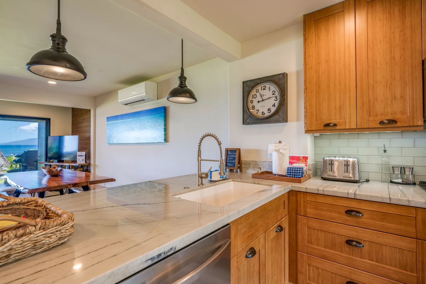 Una cocina con encimera de aspecto marmoleado, gabinetes de madera y un comedor al fondo.