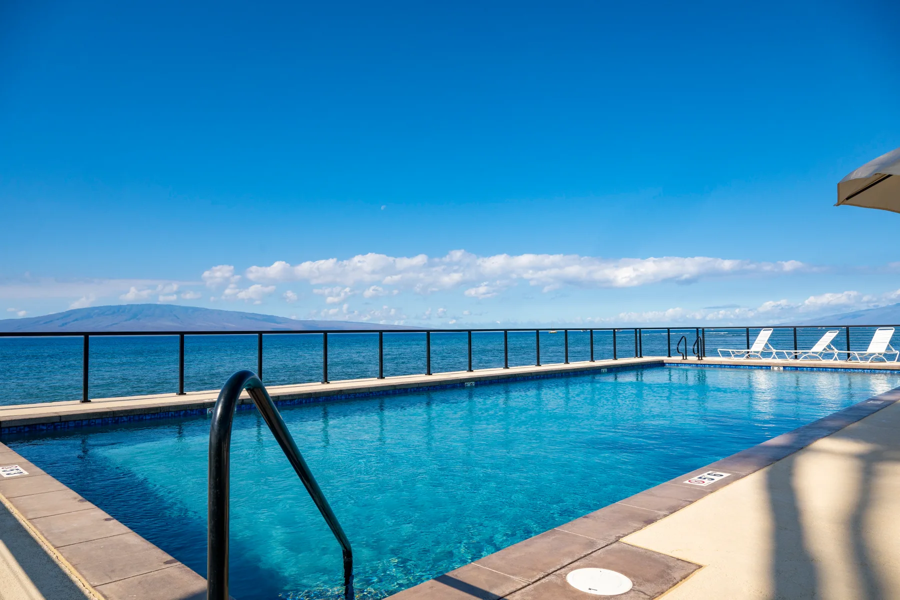 Una piscina al aire libre ofrece vistas al mar bajo un cielo azul despejado.