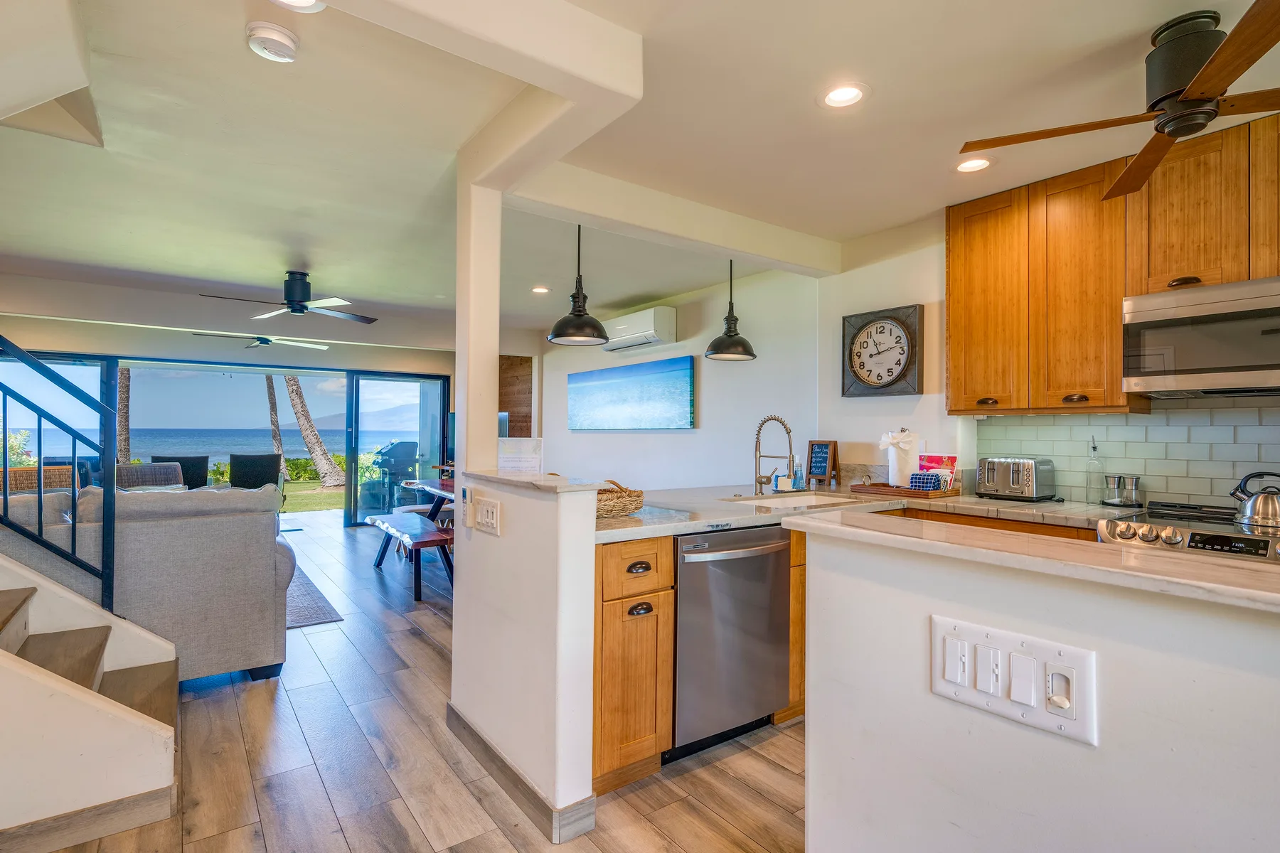 Una cocina abierta al salón, con muebles de madera y vistas a través de puertas de vidrio.