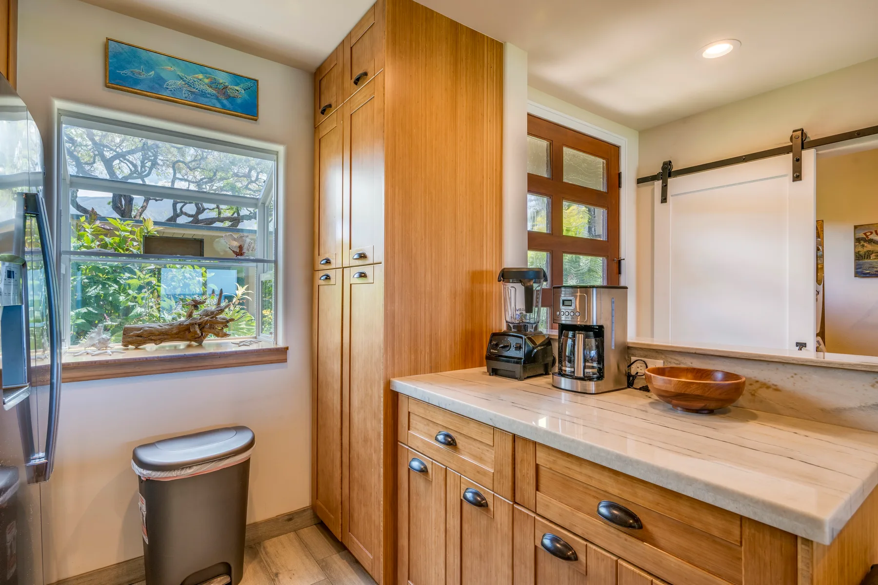 Una cocina con gabinetes de madera, una encimera y una ventana con vista a la vegetación.