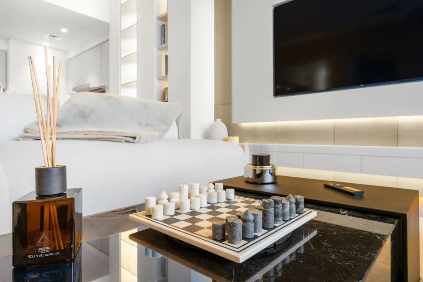 A bright bedroom with a neatly made bed and a chessboard on the table.