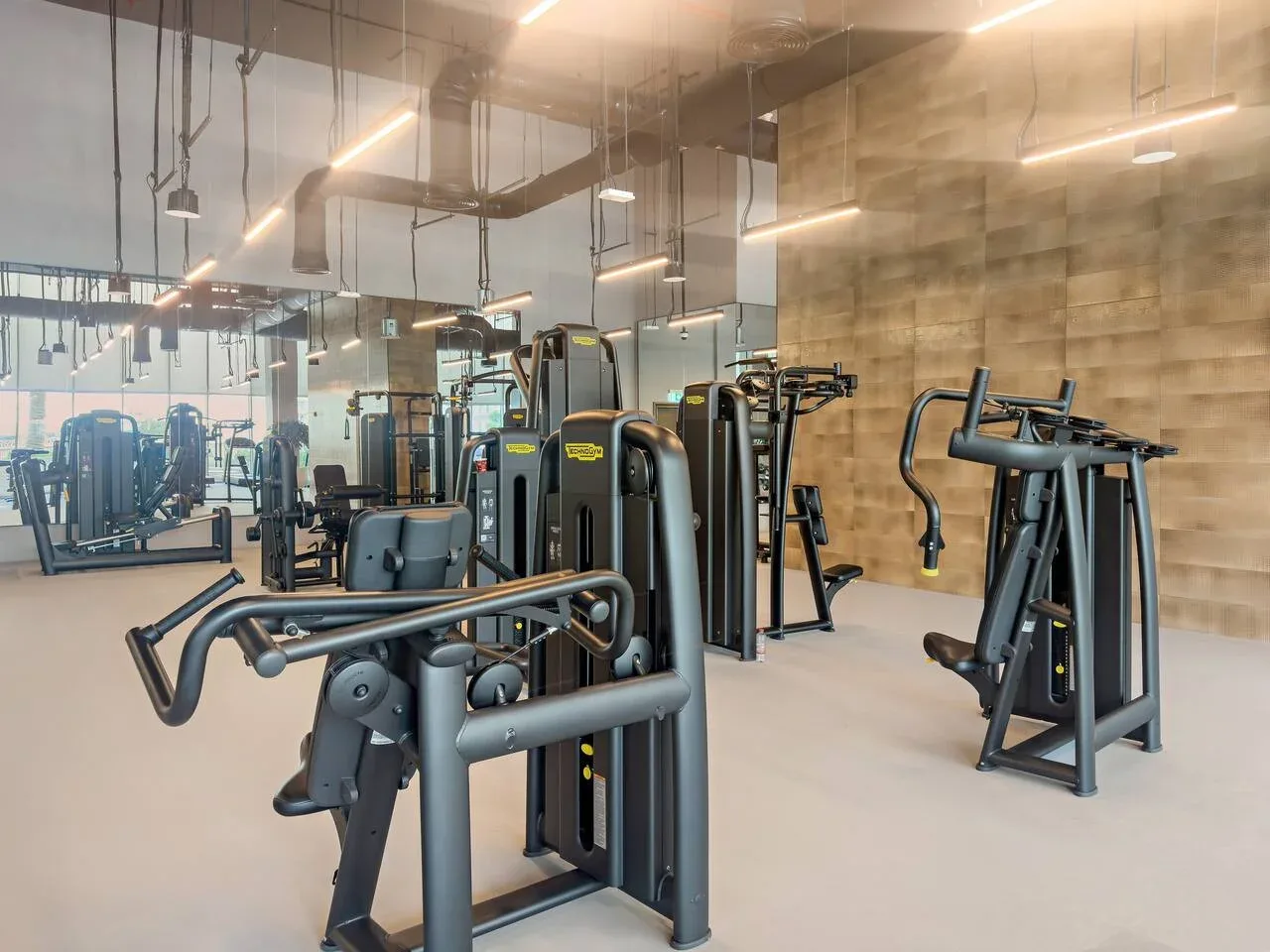 A gym with exercise machines arranged across a bright, mirrored room.