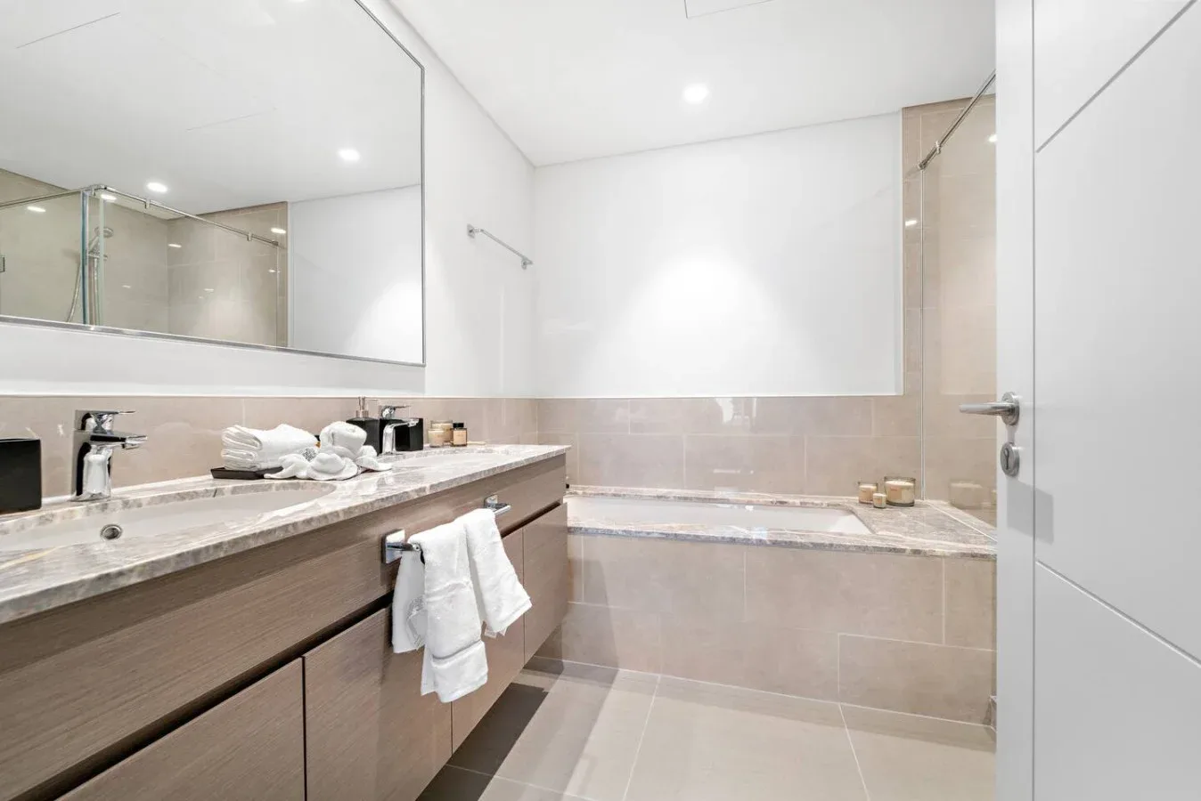 A bright bathroom with a long vanity and a bathtub.