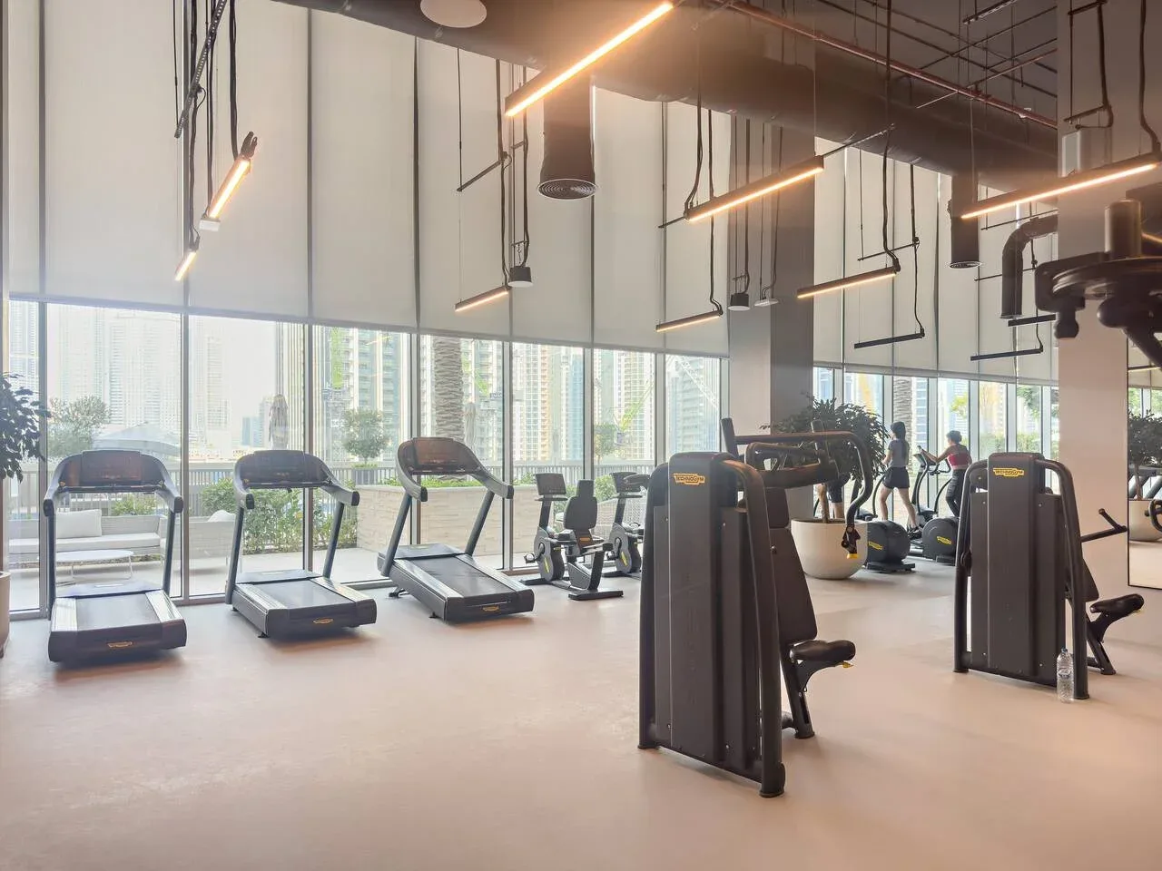 A gym with treadmills, exercise machines, and large windows.