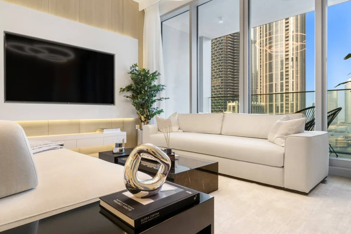 A bright living room with pale seating and floor-to-ceiling windows.