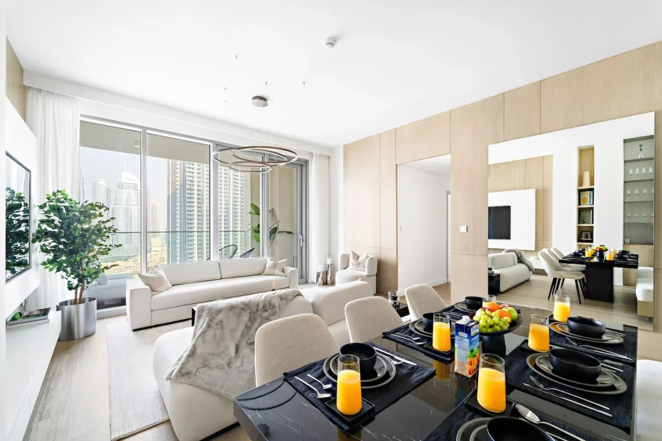 A bright living and dining area with large windows and a set dining table.