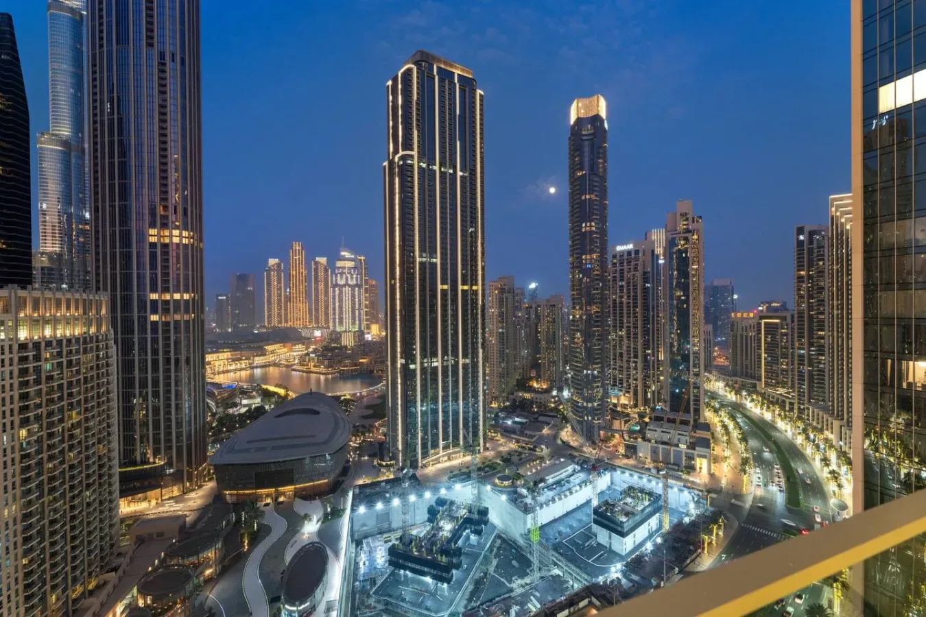 A nighttime city skyline with illuminated high-rise buildings and roads.