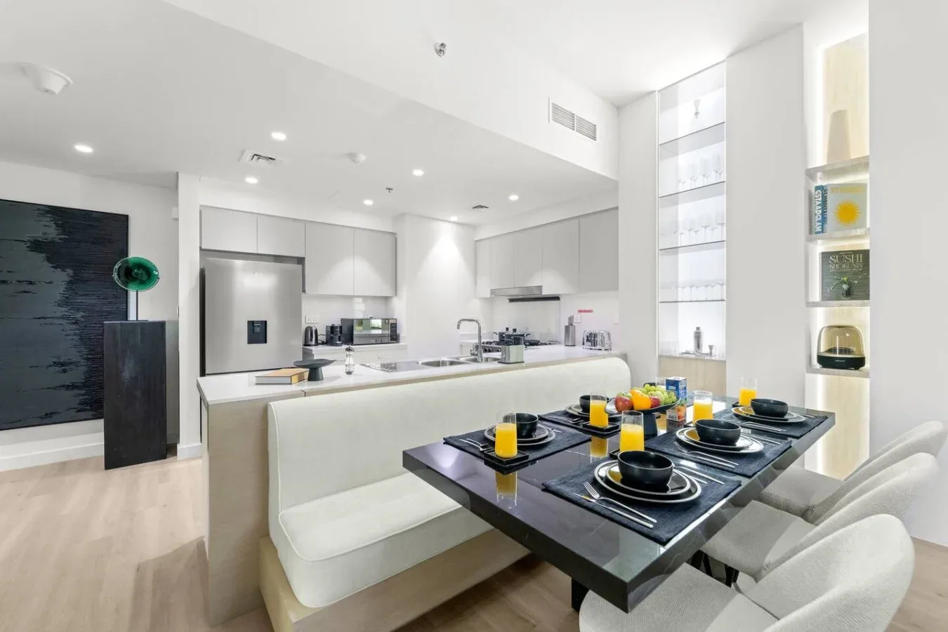 A bright open-plan kitchen and dining area with a set table and built-in seating.