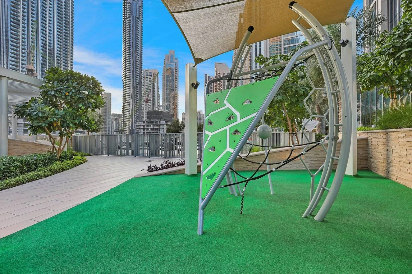 A rooftop recreation area features green artificial turf and a curved climbing structure.