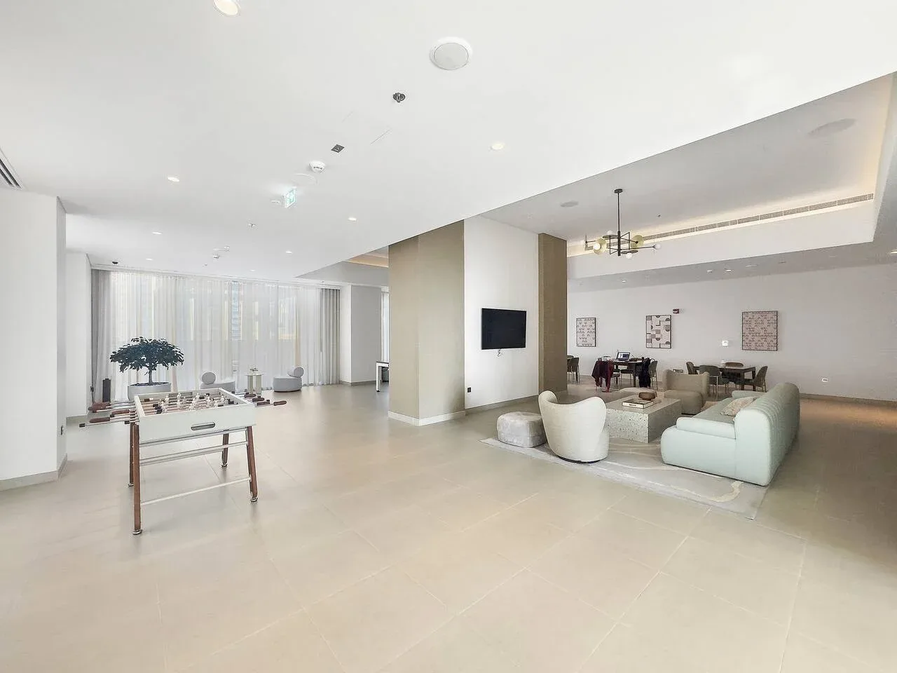 A bright open-plan lounge and dining area with pale seating and large windows.