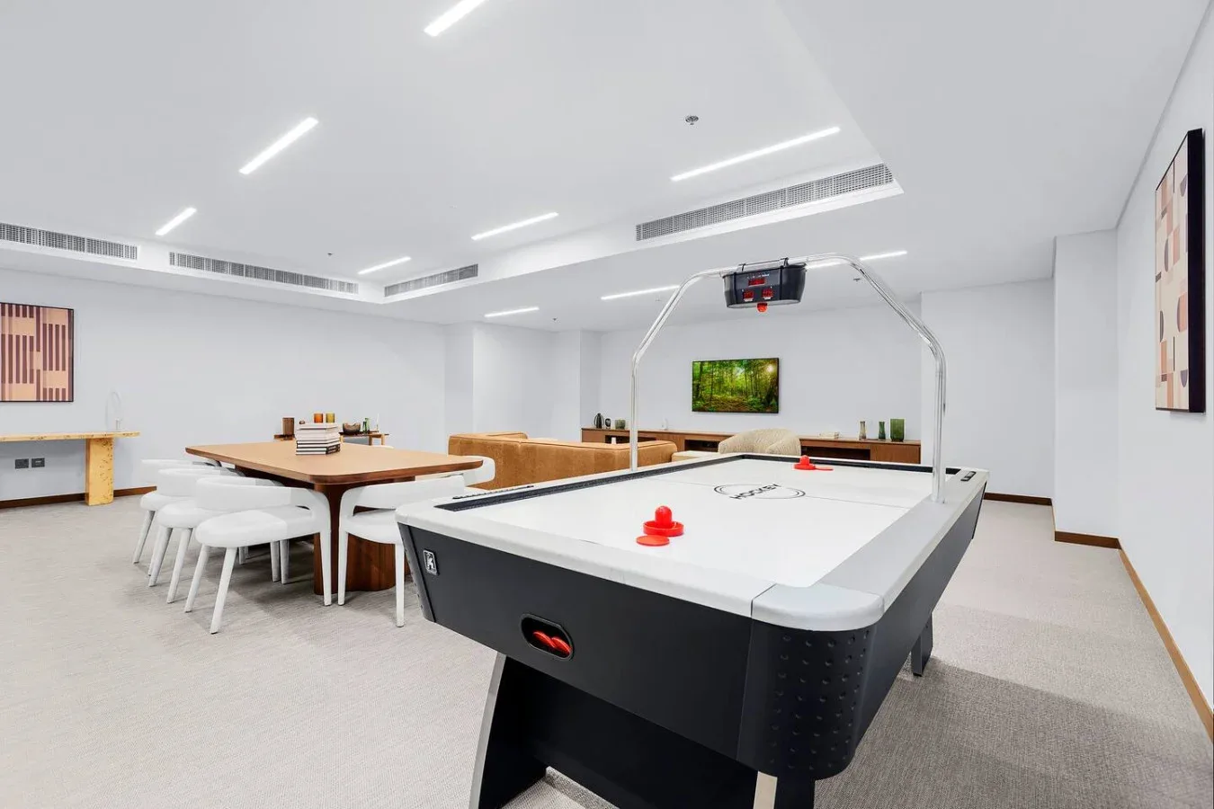 A bright recreation room features an air hockey table and a dining table with seating.