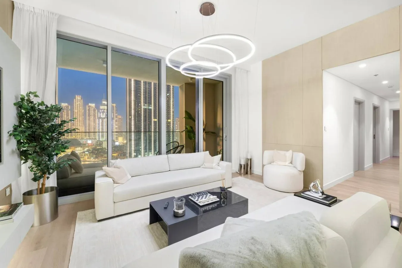 A bright living room with seating beside large windows overlooking a city skyline.