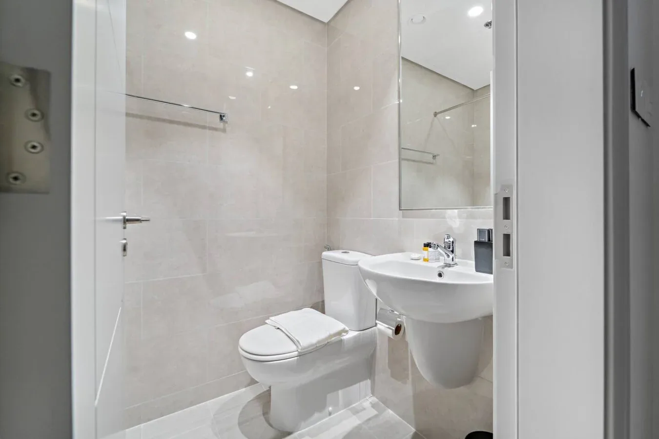 A bright bathroom with a toilet, sink, and large wall mirror.