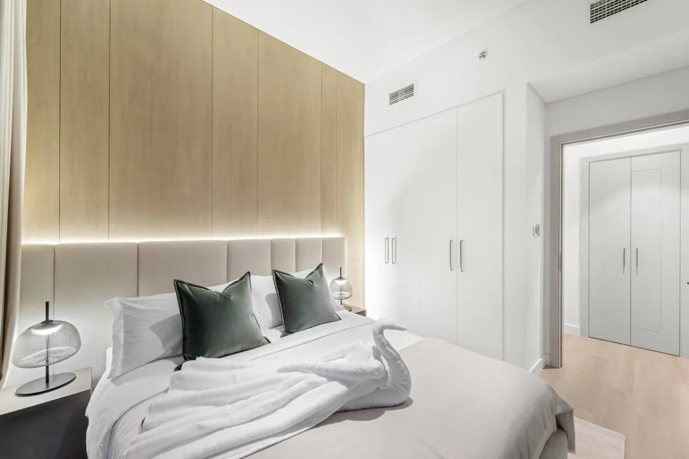 A bright bedroom with a neatly made bed and built-in wardrobes.