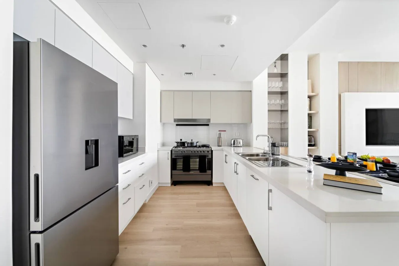 A modern kitchen with white cabinets, a large refrigerator, and a central island.
