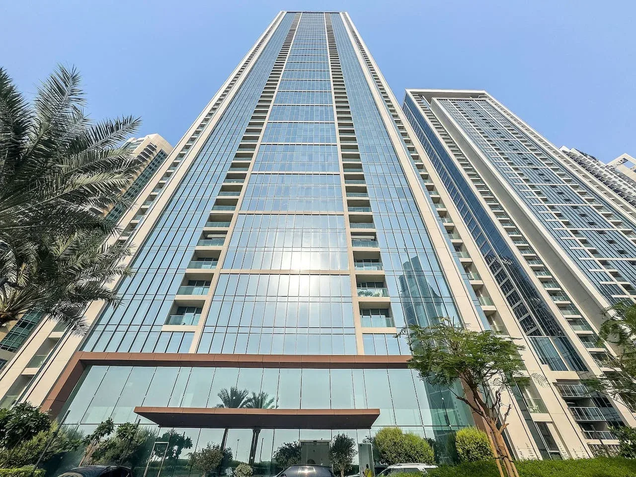 A low-angle view of tall glass-fronted buildings beside palm trees.