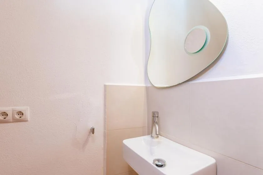 Un lavabo y un grifo de baño están debajo de un espejo de pared.