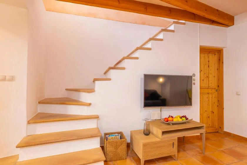 Una sala de estar con un televisor debajo de una escalera de madera.