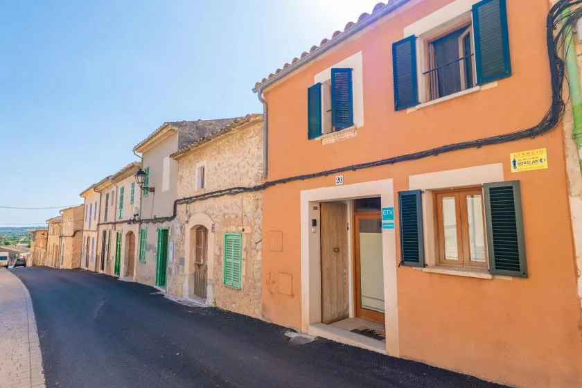 Una calle bordeada de edificios coloridos, incluida una fachada naranja con contraventanas azules.