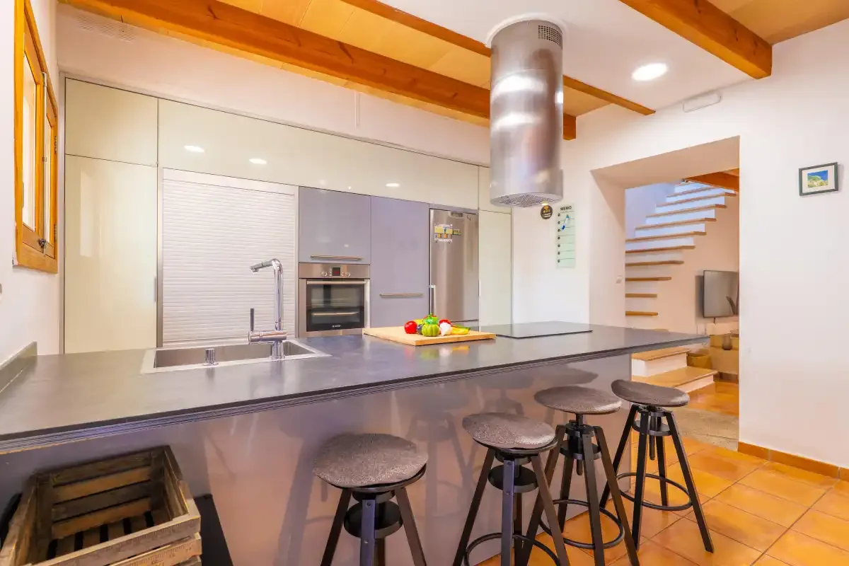 Una cocina moderna con una barra larga y varios taburetes.